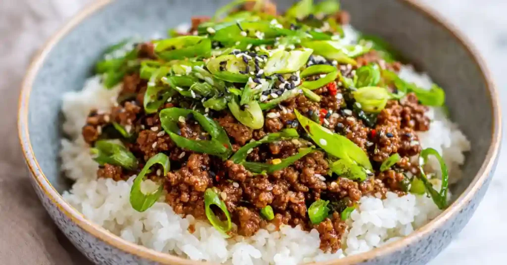 Korean ground beef bowl served over jasmine rice with green onions and sesame seeds