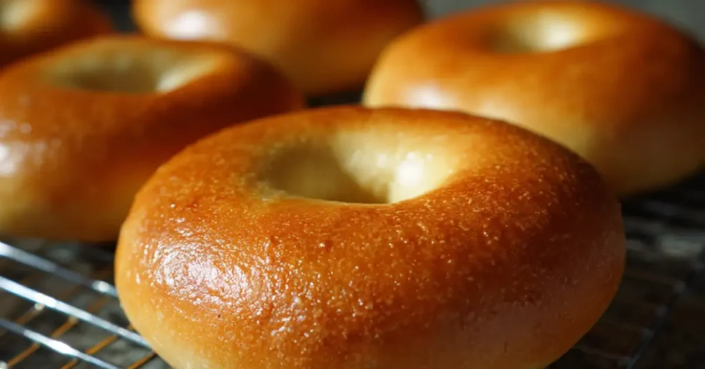 Homemade bagels with a golden crust cooling on a rack in a bright kitchen.